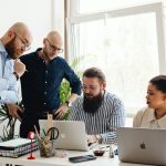 Team collaborating on business strategy around laptop in modern office