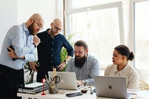 Team collaborating on business strategy around laptop in modern office